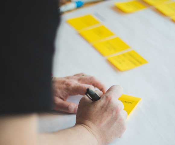 holding white paper and sticky notes on table - Photo by Brands&People on Unsplash